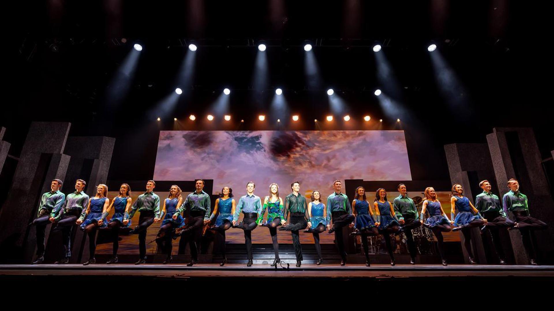 A group of performers dancing in a line on stage.
