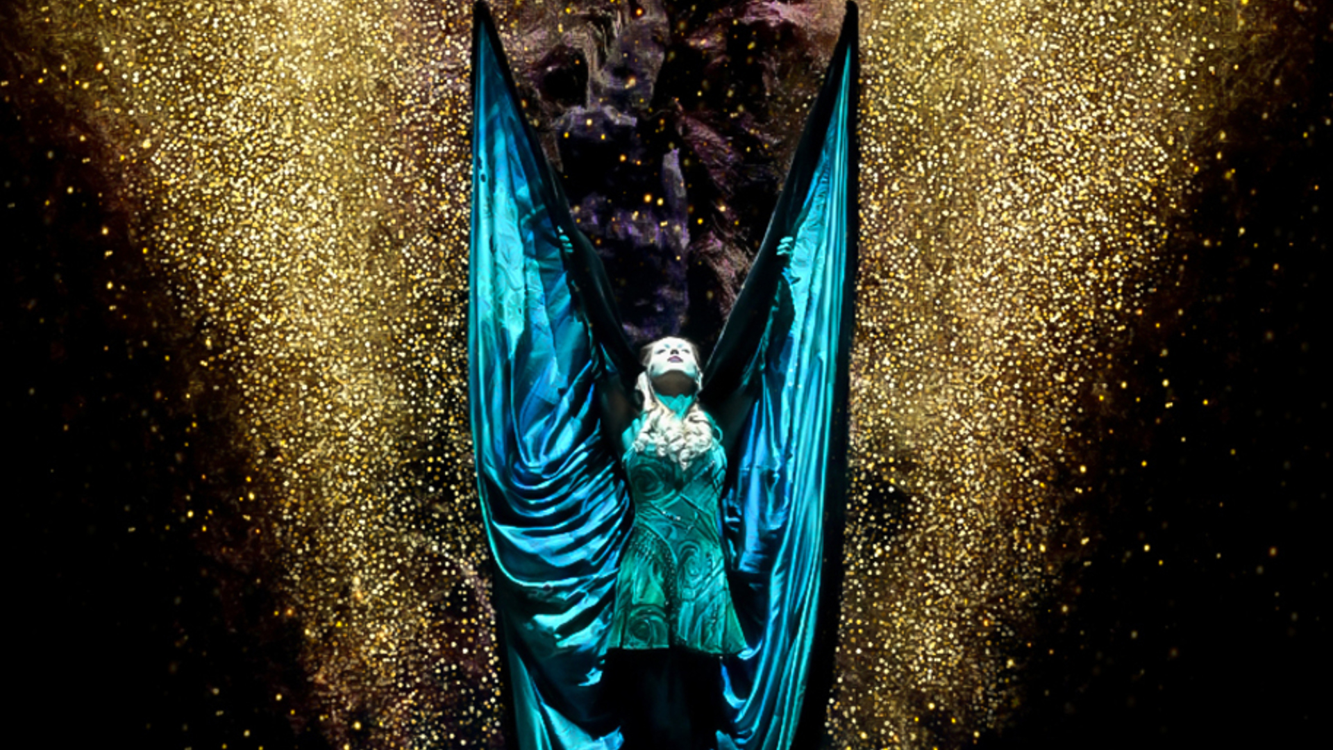A performer standing with a large cloak behind them, resembling wings.