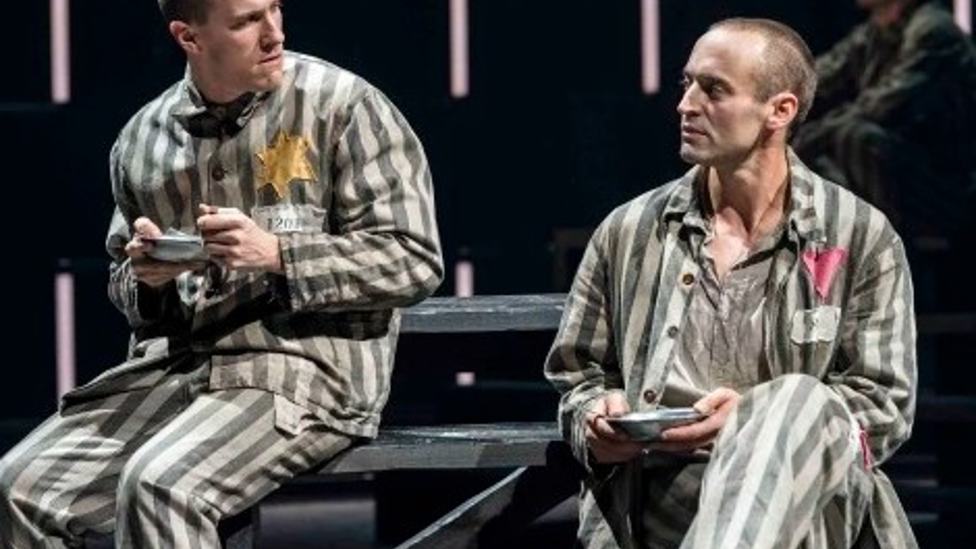 2 actors sitting in prisoner costumes performing in the production of Bent