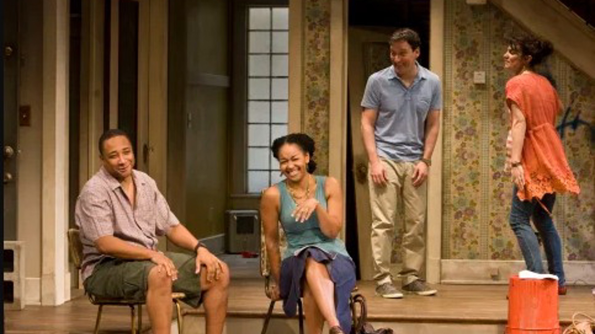 two men and two women, two are sitting and two standing all are laughing