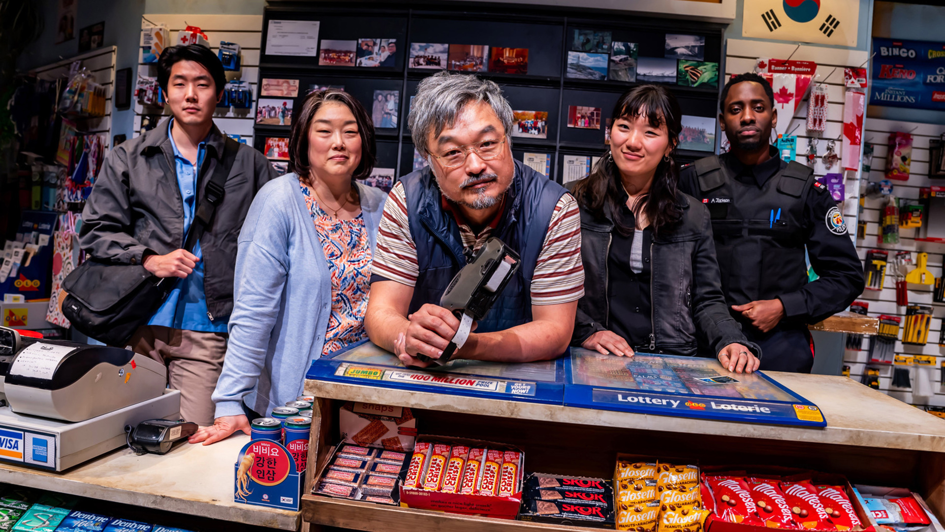 Five people pose together behind the counter of a convenience store.