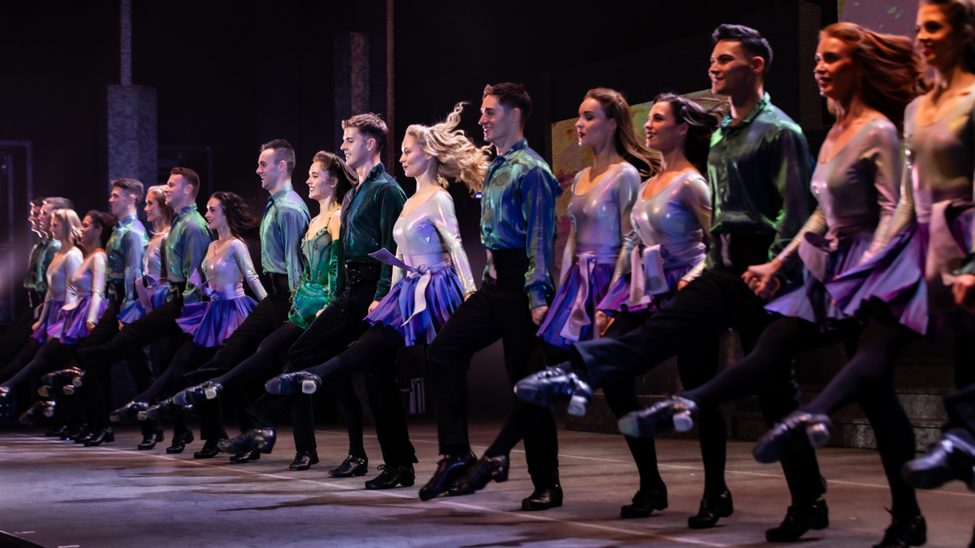 A group of performers dancing in a line on stage.