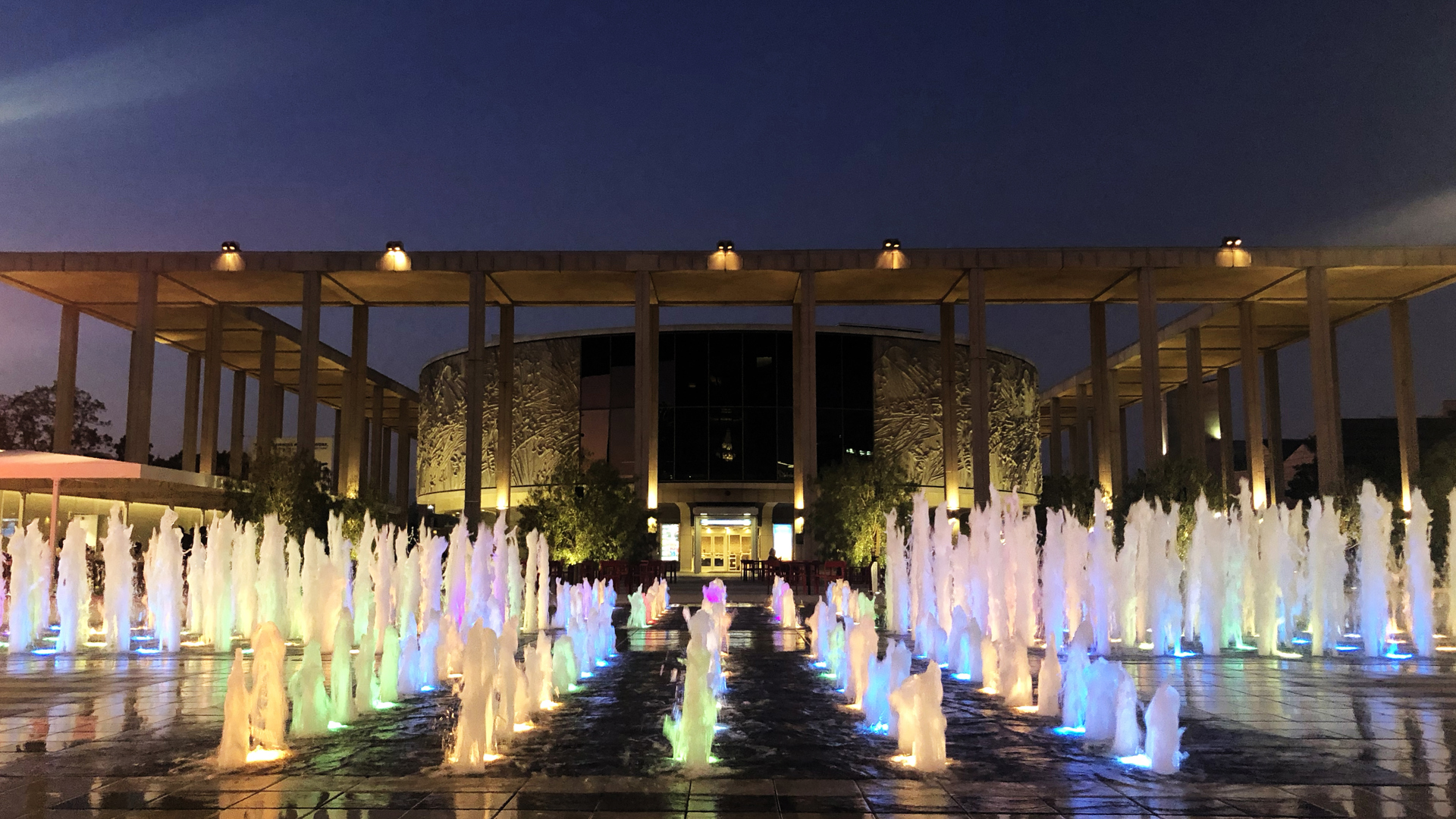 The front of the Mark Taper Forum, color water shoots up. 