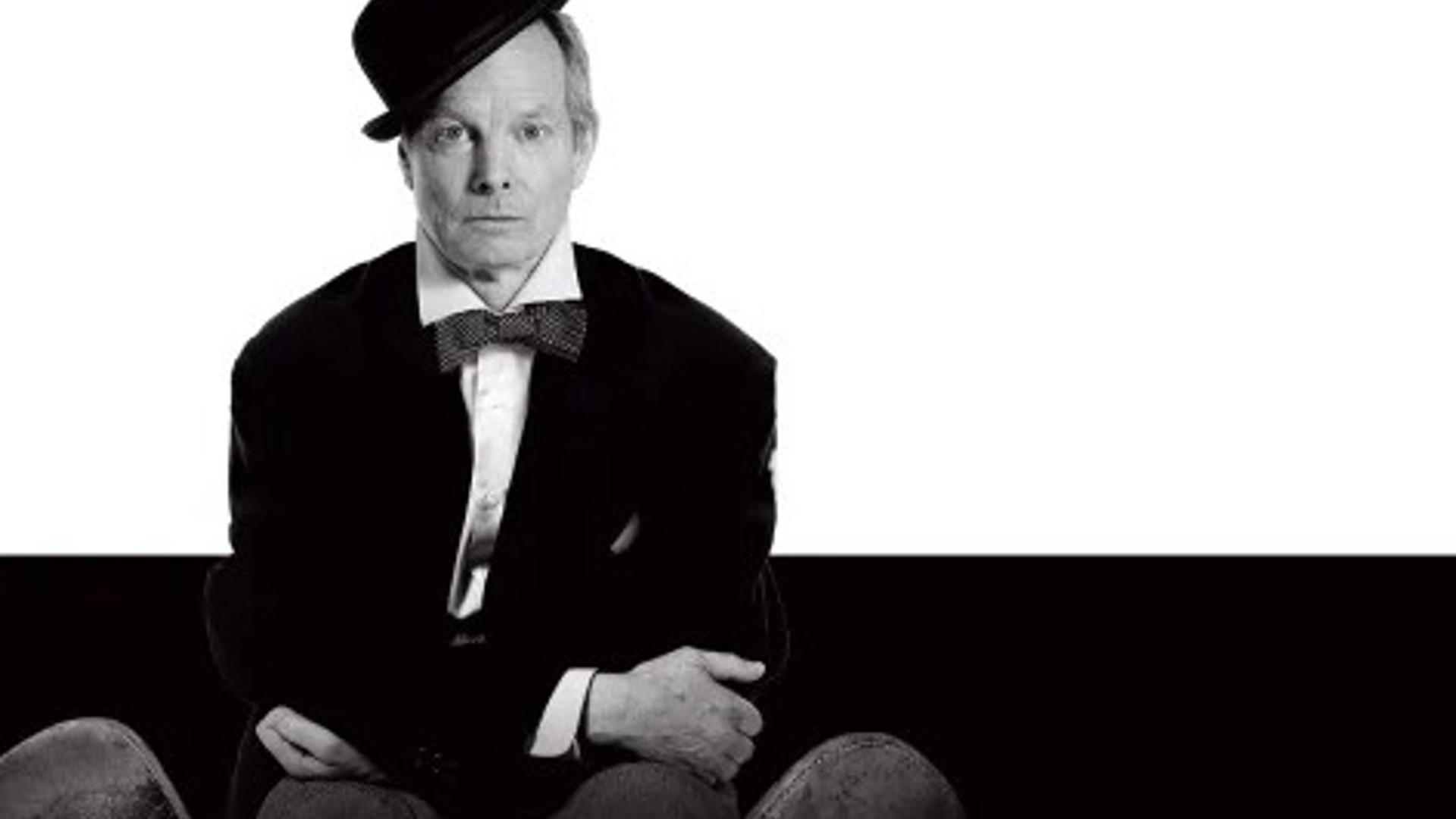 Bill Irwin in a hat and bow tie sitting for On Beckett at the Kirk Douglas Theatre 