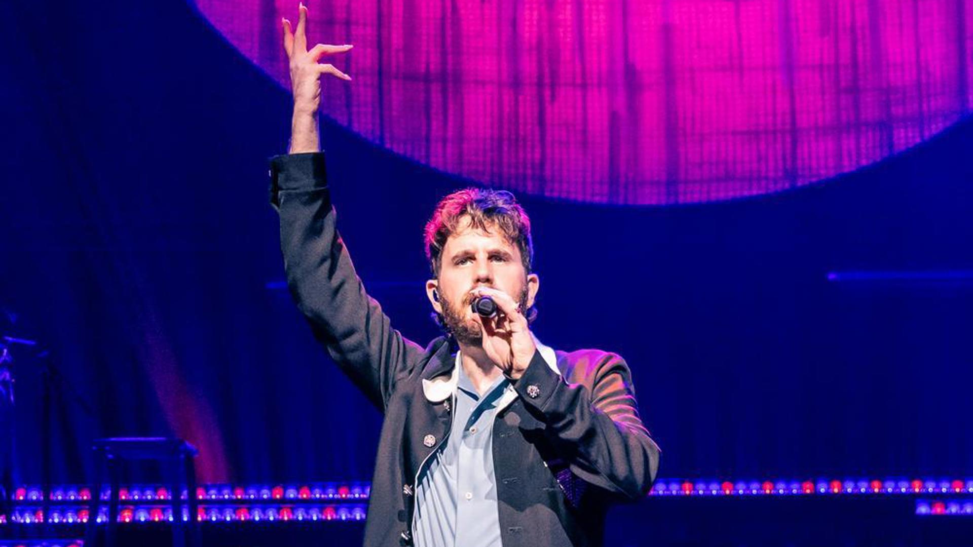 Ben Platt on stage under blue and pink lighting with a large circular backdrop.