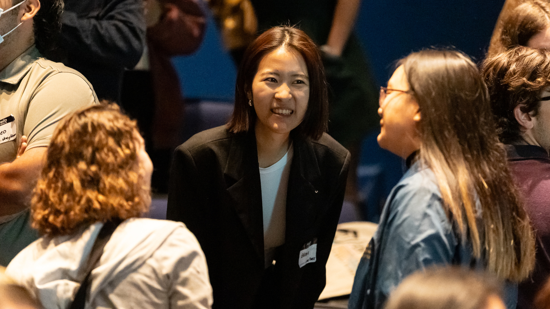 A presenter is leaning in to the conversation of two people. 