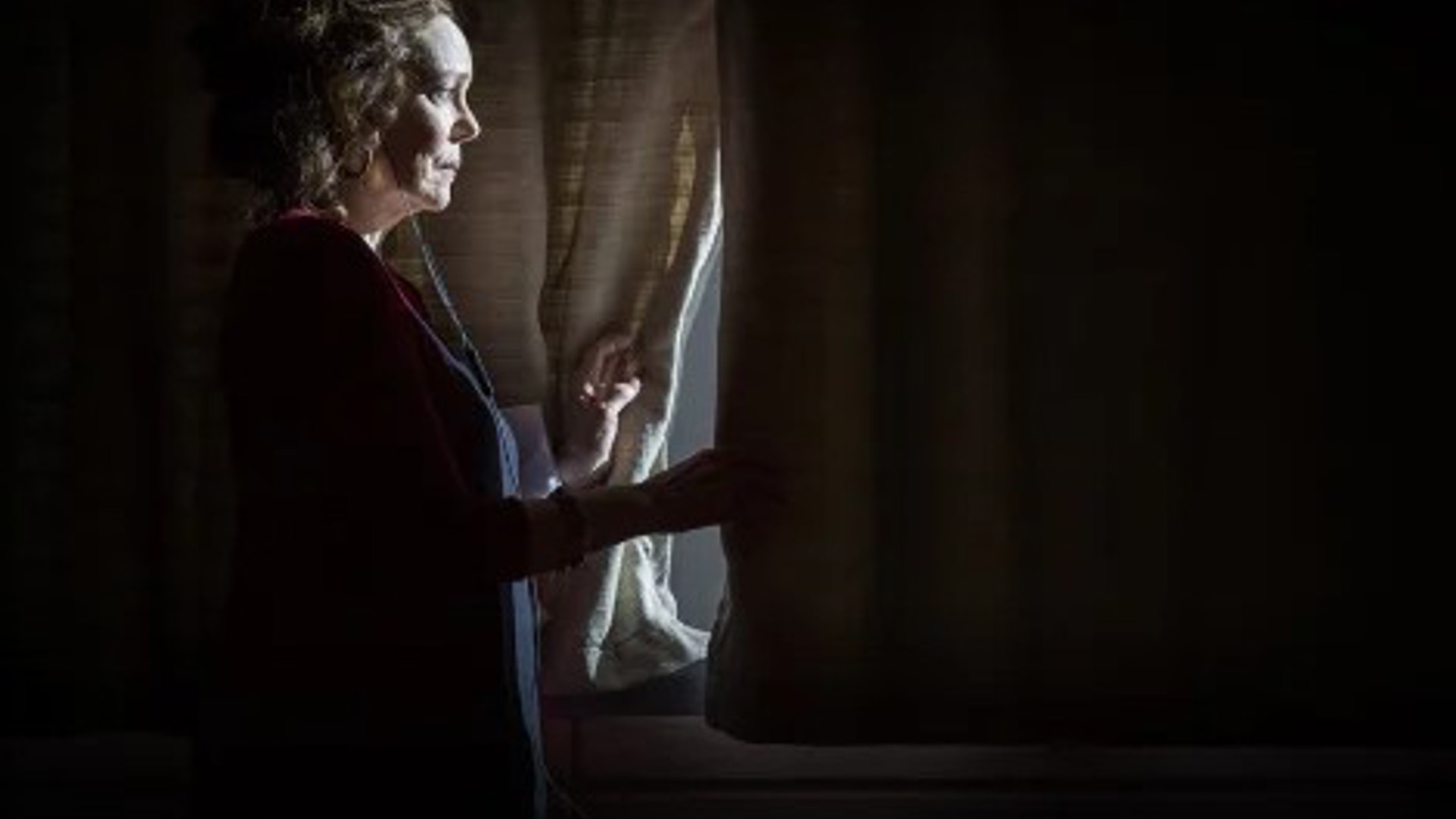 Deirdre O’Connell looking out a window in a dramatic play