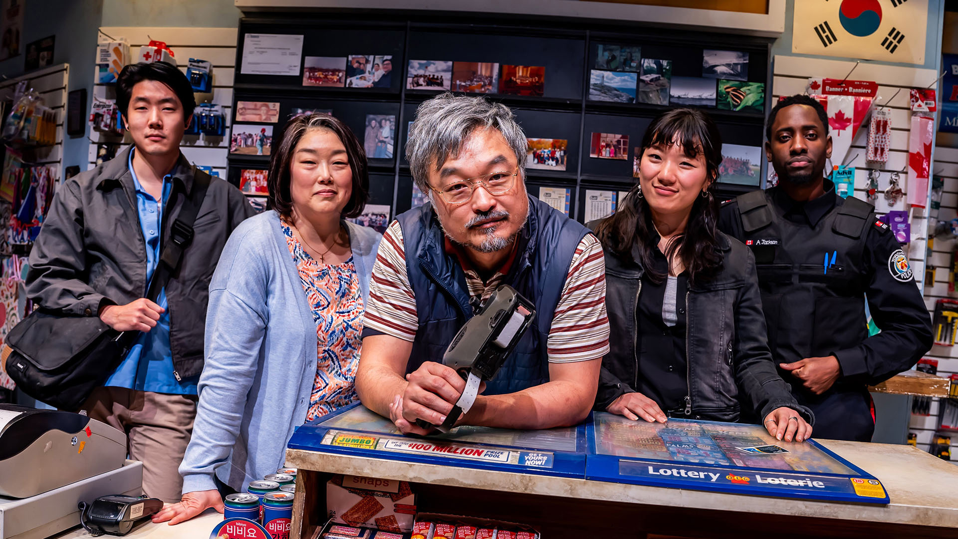 Five people pose together behind the counter of a convenience store.