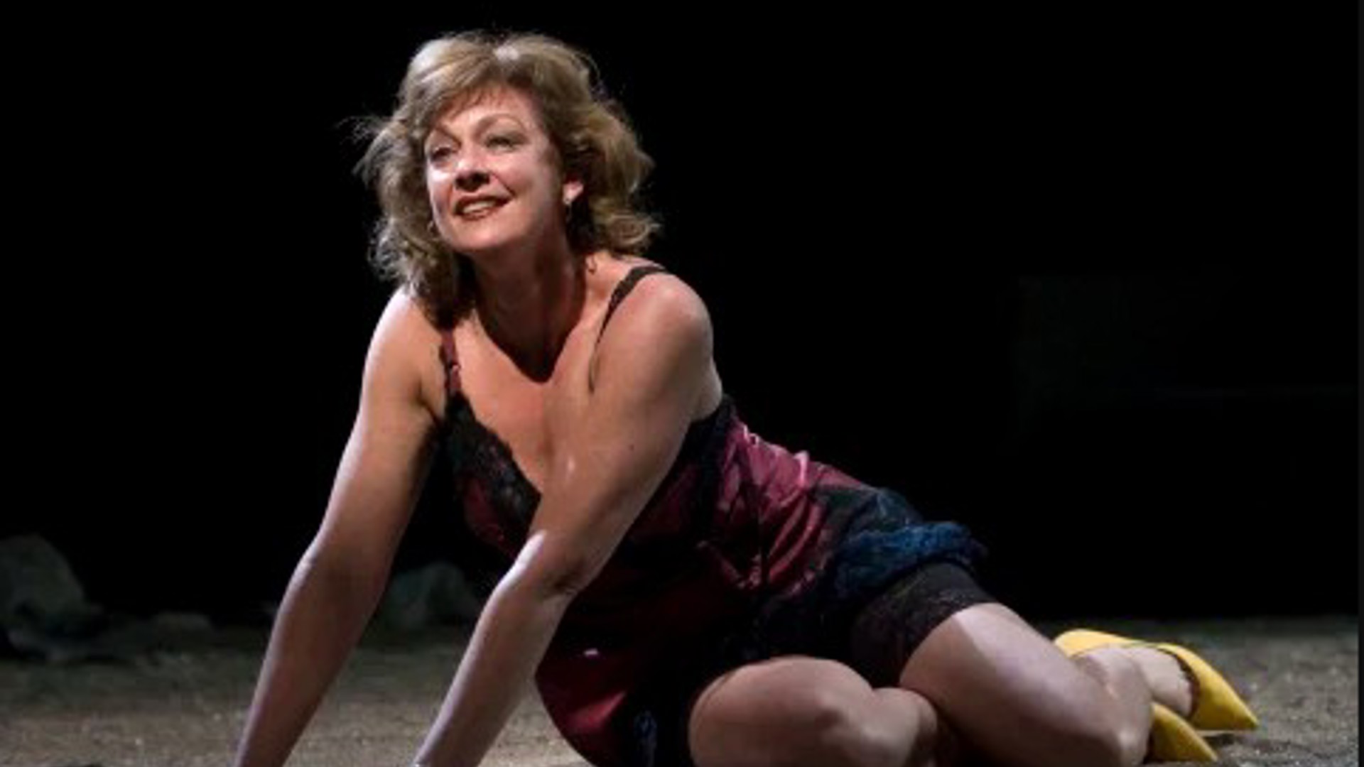 beautiful actress part kneeling part lying on stage in a dress and yellow pumps heels