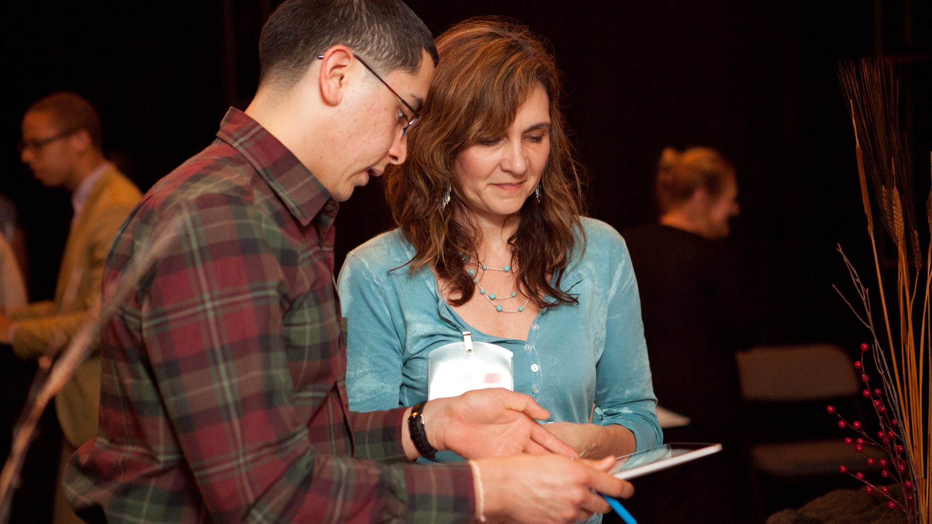 Two people review and discuss content on a tablet.