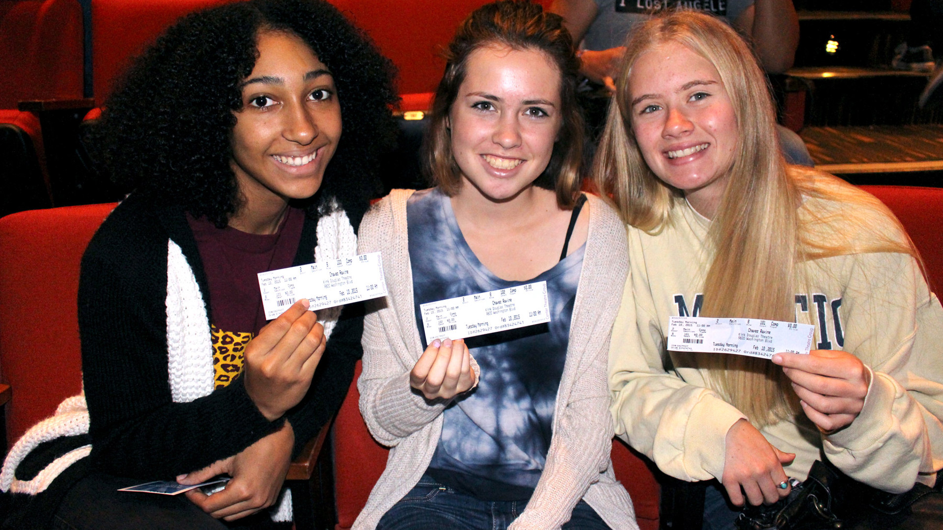 Three audience members posing with their tickets. 