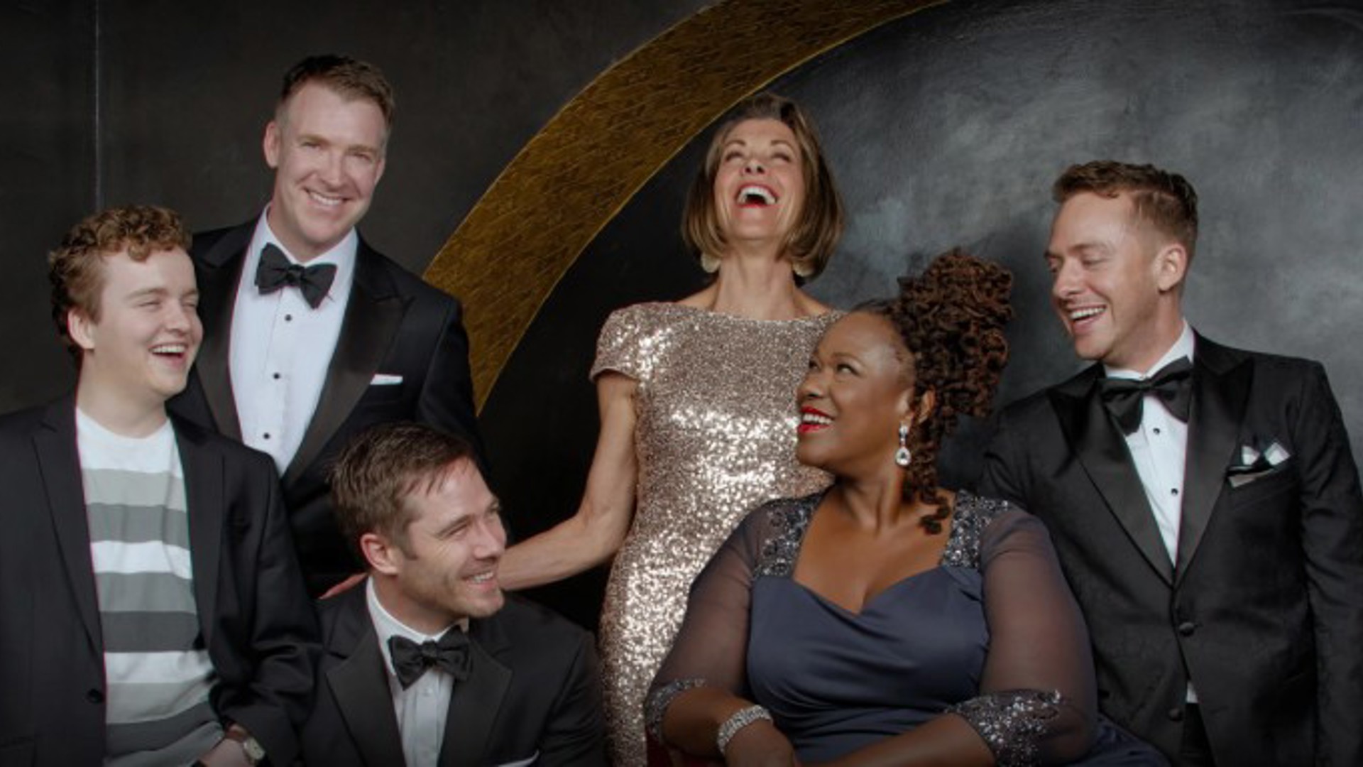 Men and women dressed for Oscar night laughing at the writing by Paul Rudnick