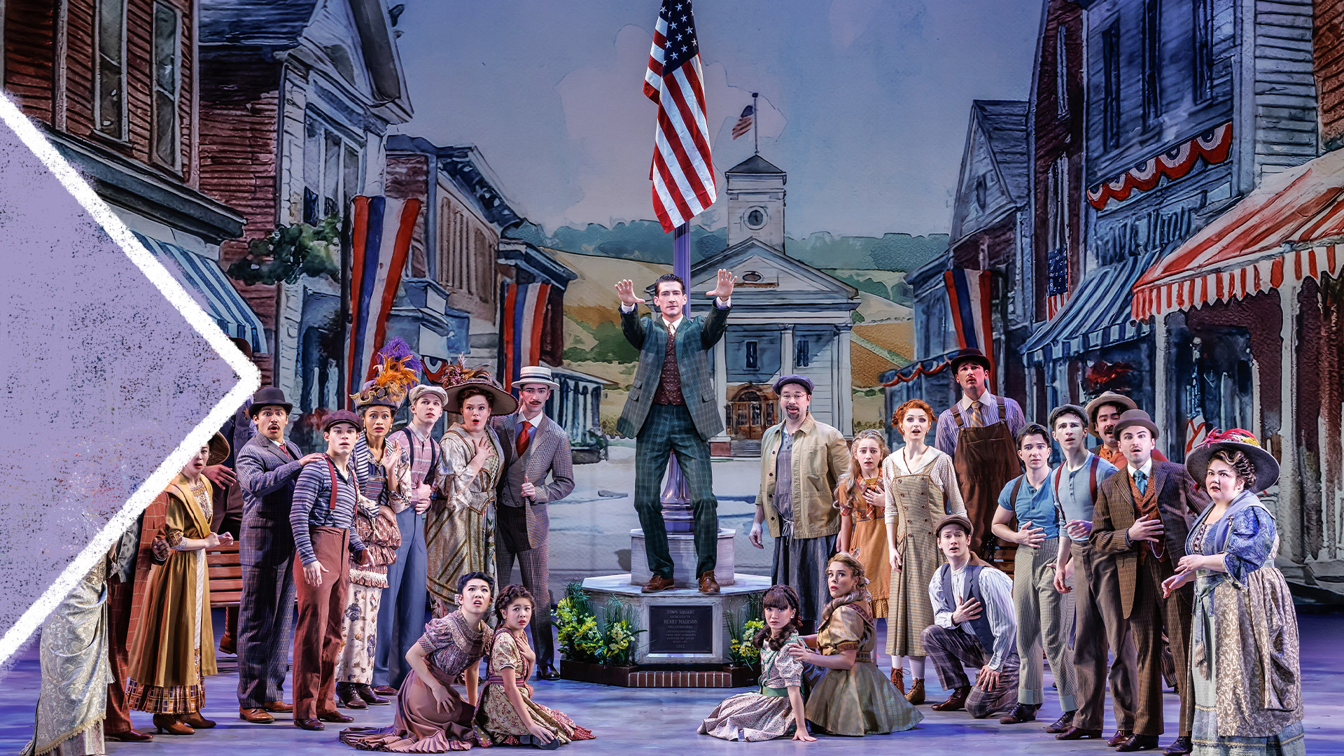 An actor stands center in the middle of the square with both arms stretched forward addressing the entire town.  