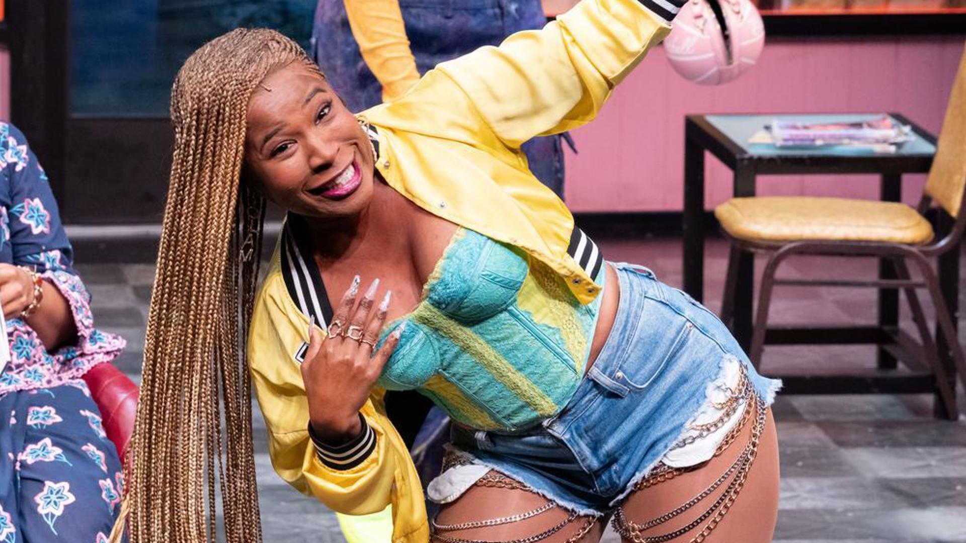 A performer stands center stage, showing off long blonde box braids.