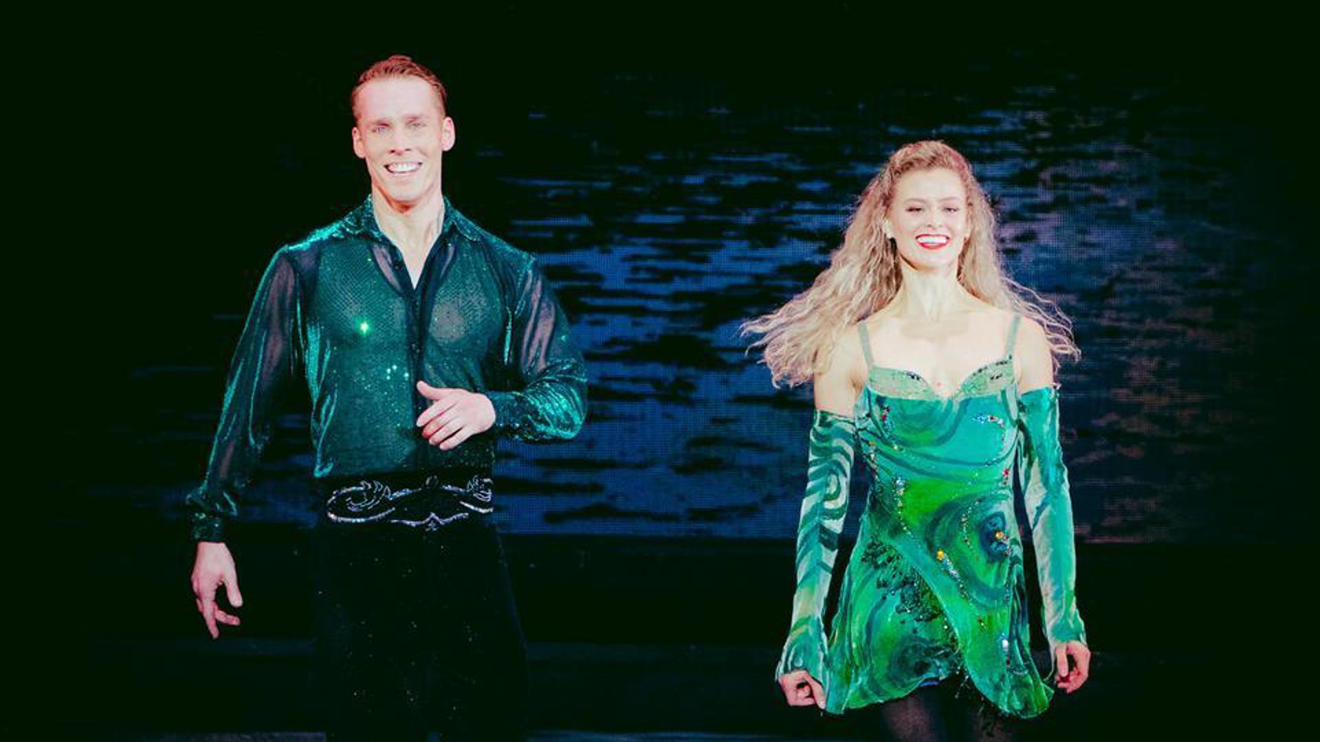 Two performers dancing side by side on stage.