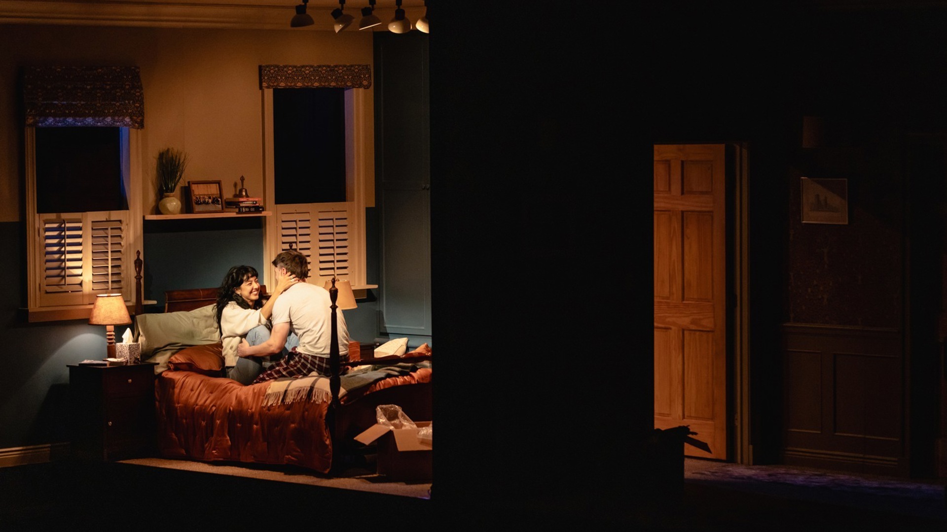 A couple sitting on a bed, holding each other.