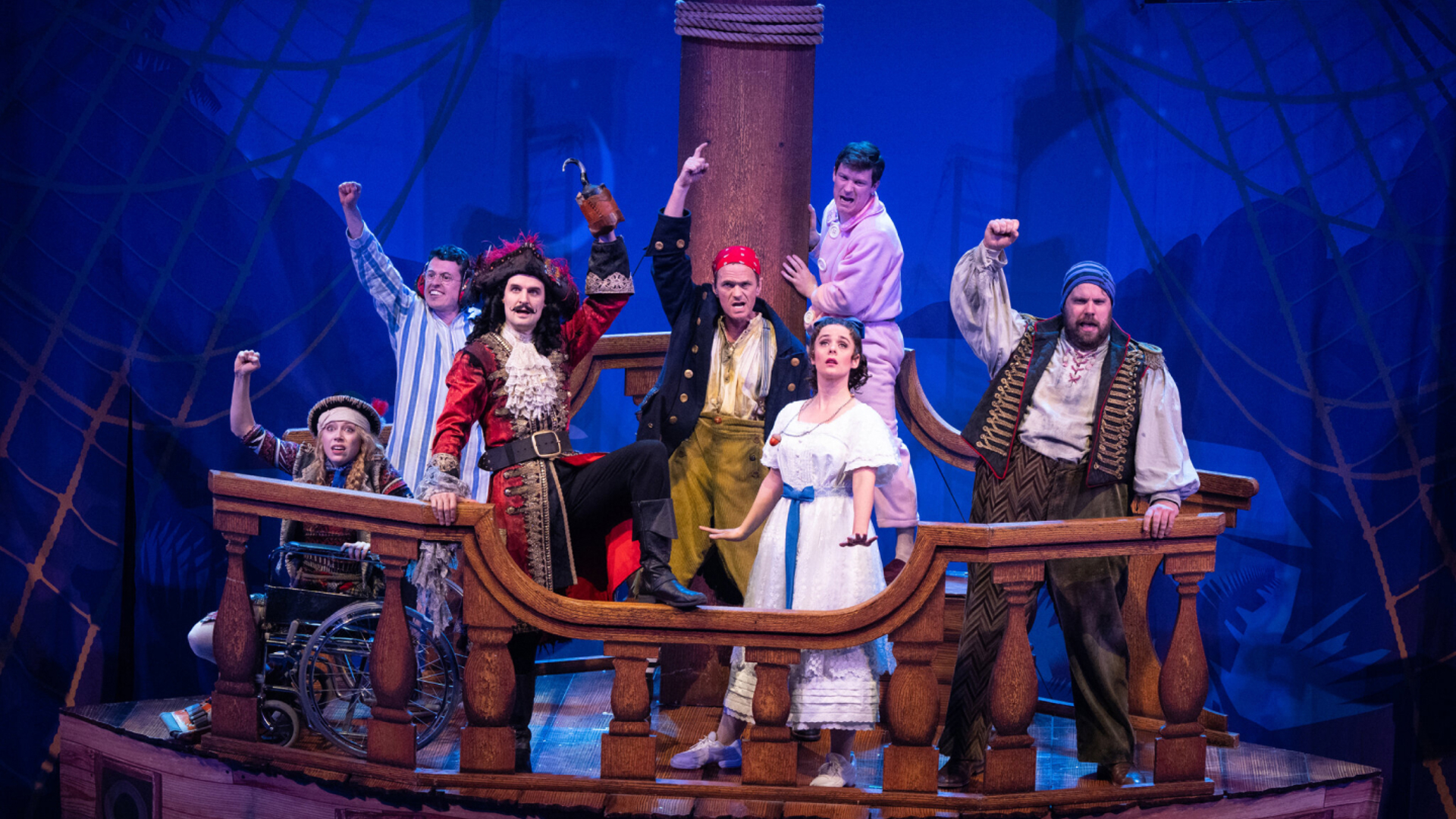 Scene from Peter Pan Goes Wrong where seven pirates are raising their fists on the deck of a ship.