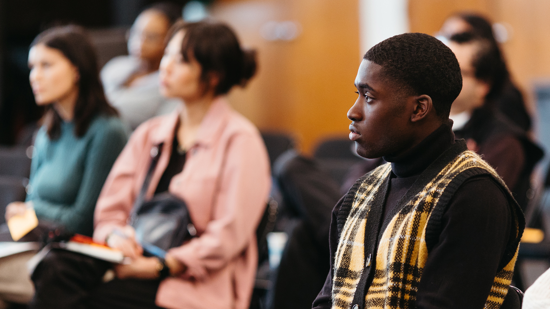 A group of young adults sit and listen. 