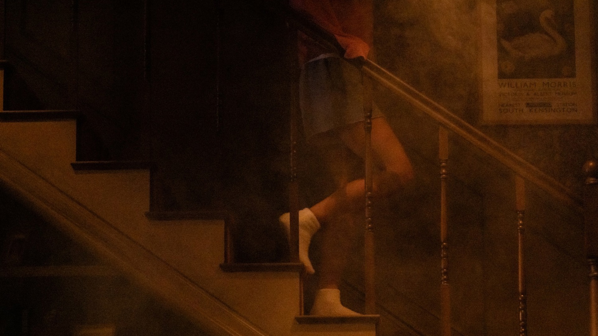 A person comes down stairs in a dark house. 