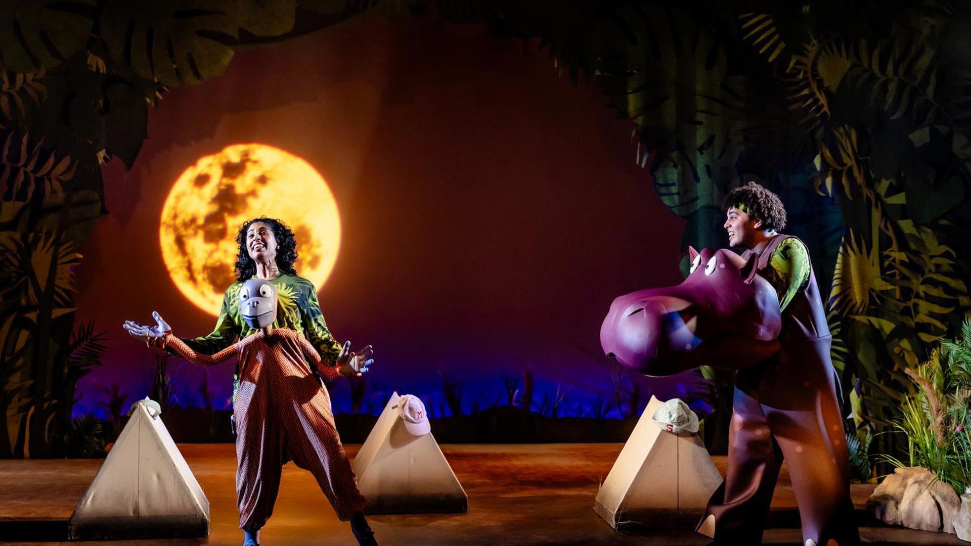 An orangutan sings in front of the moon while a hippo watches.