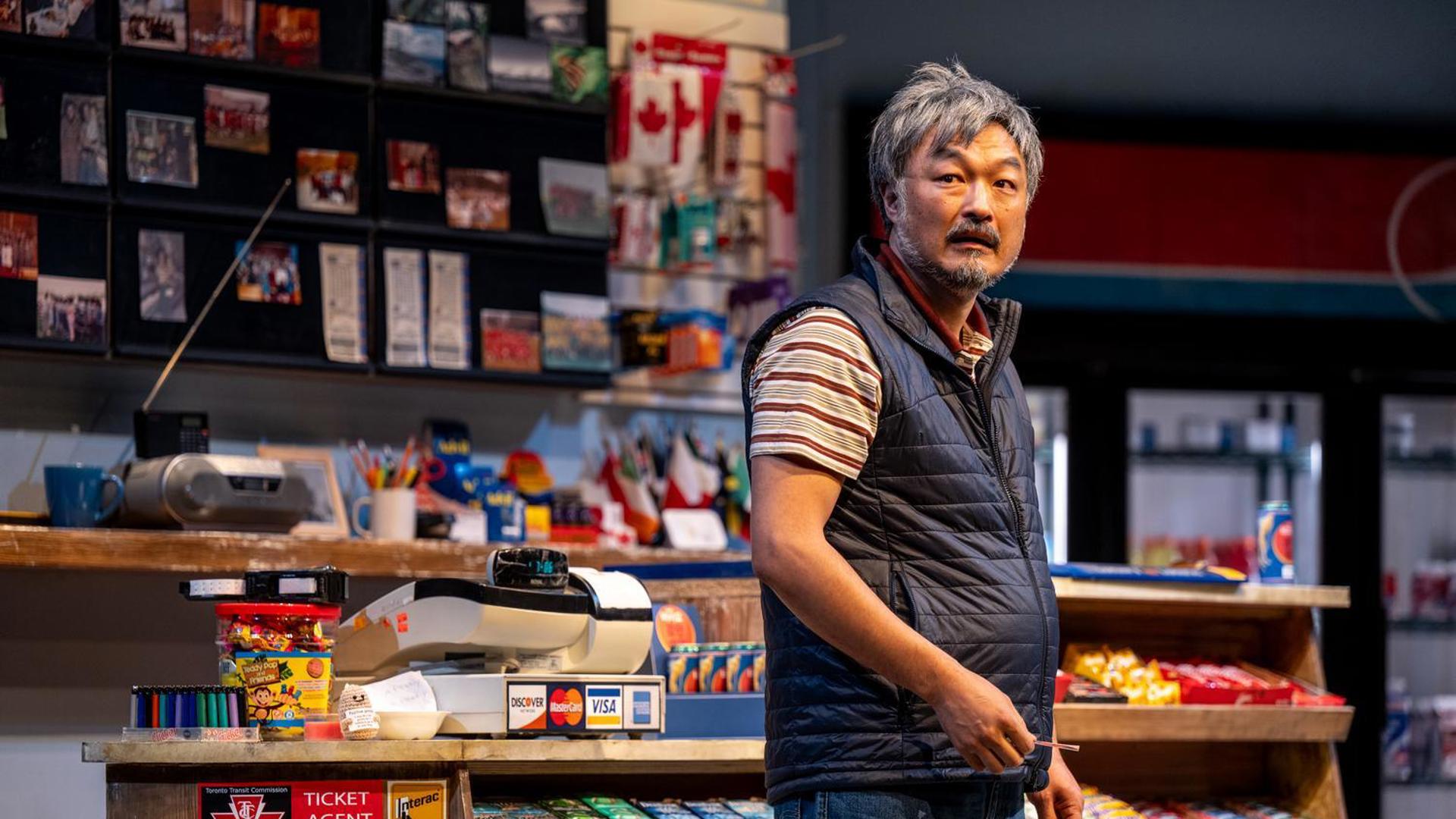 A man stares out to a distance in a convenience store. 